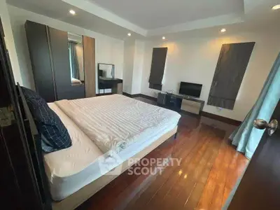 Spacious bedroom with wooden flooring and modern furnishings in a stylish apartment.