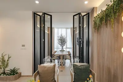 Elegant living room with folding glass doors leading to a stylish dining area, featuring modern decor and lush greenery.