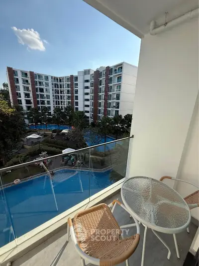 Modern balcony with glass railing overlooking pool and residential complex