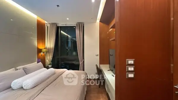 Luxurious bedroom with modern design and city view, featuring elegant lighting and wooden accents.