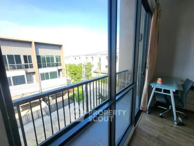 Spacious balcony with a view of modern buildings and greenery, perfect for relaxation.