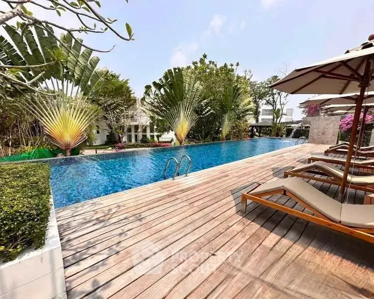 Luxurious outdoor pool area with sun loungers and lush greenery, perfect for relaxation and leisure.
