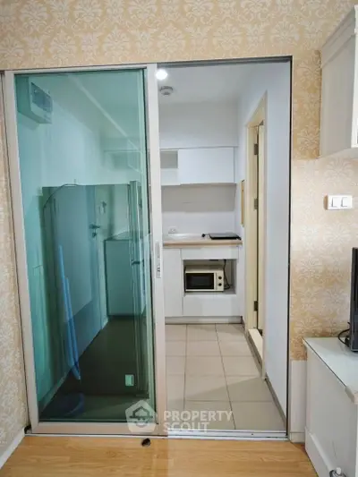 Modern kitchen with sliding glass door and built-in microwave in stylish apartment.
