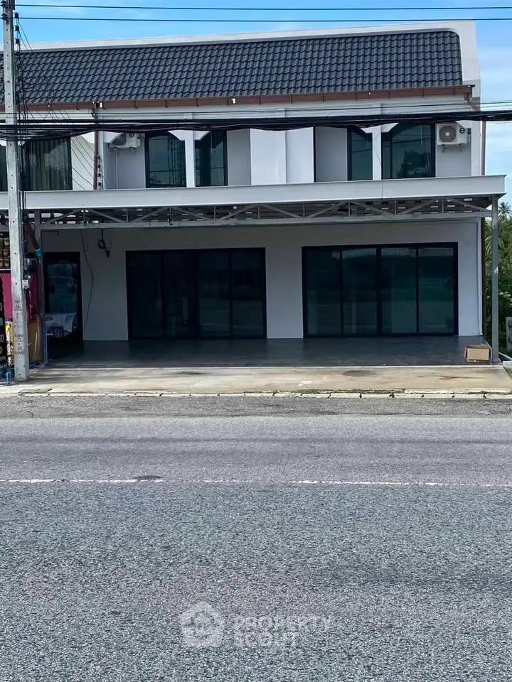 Modern commercial building with large glass windows and spacious parking area.