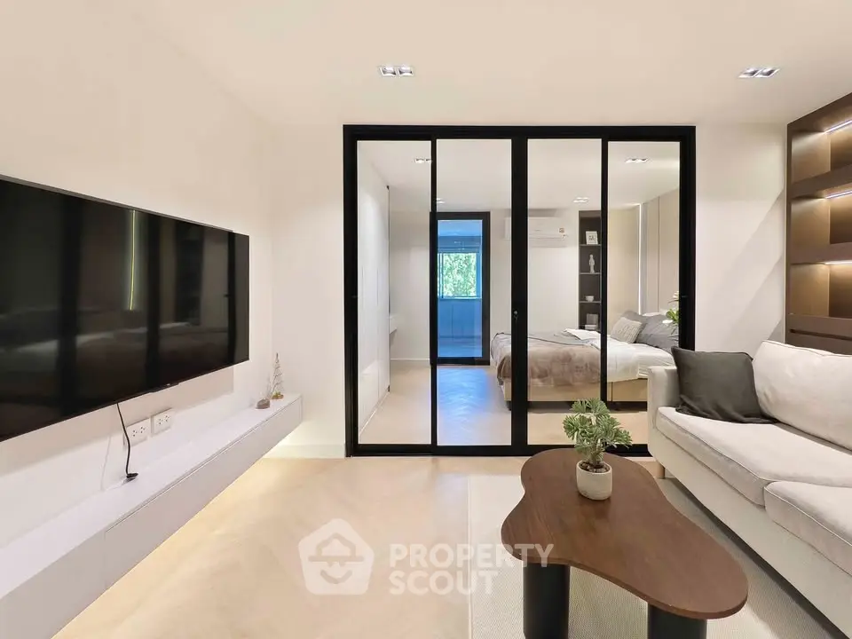 Modern living room with sleek design and large TV, featuring a cozy sofa and stylish coffee table.