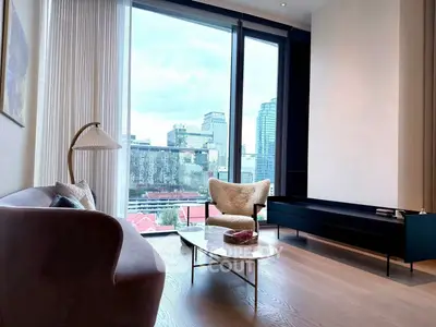 Modern living room with city view, featuring elegant furniture and large windows.