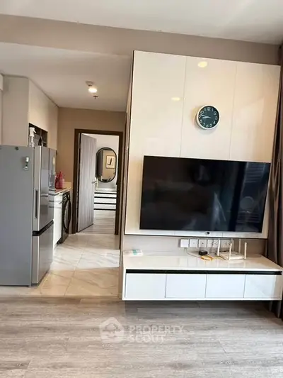 Modern living room with sleek TV setup and kitchen appliances in open layout