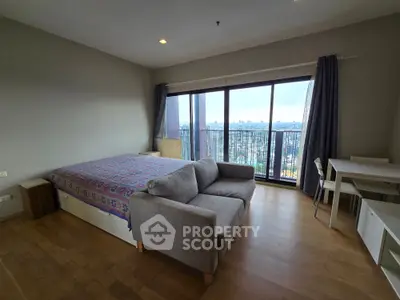 Spacious bedroom with large windows offering stunning city views, featuring a cozy sofa and modern decor.
