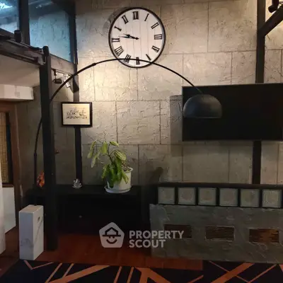 Stylish living room with modern decor, large clock, and unique lighting fixture.