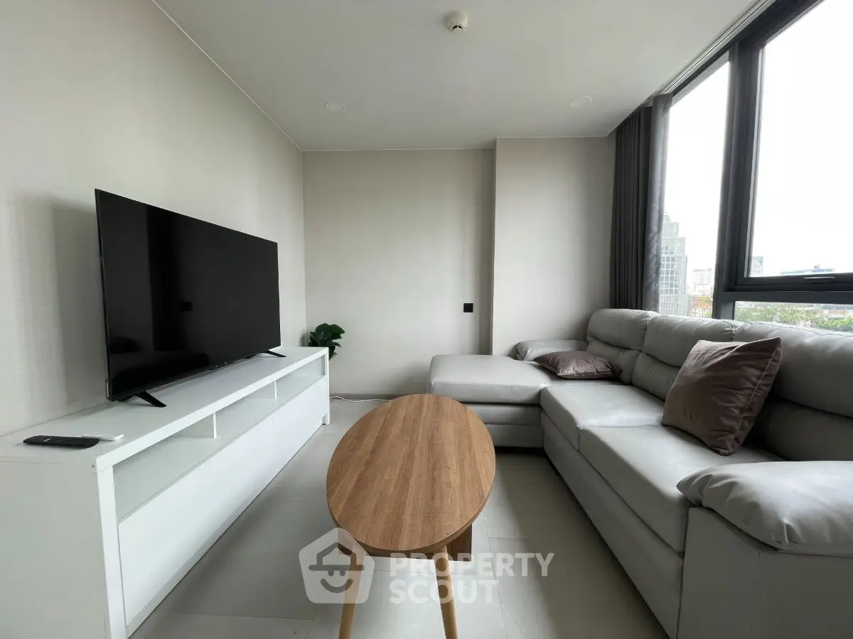 Modern living room with sleek furniture and large TV, offering a cozy and stylish ambiance.