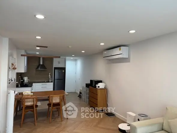 Modern open-layout living room with kitchen, featuring sleek furniture and appliances.