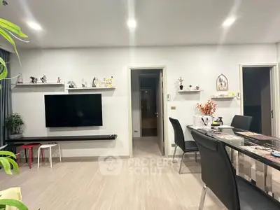 Modern living room with sleek decor and dining area, featuring a wall-mounted TV and stylish furniture.