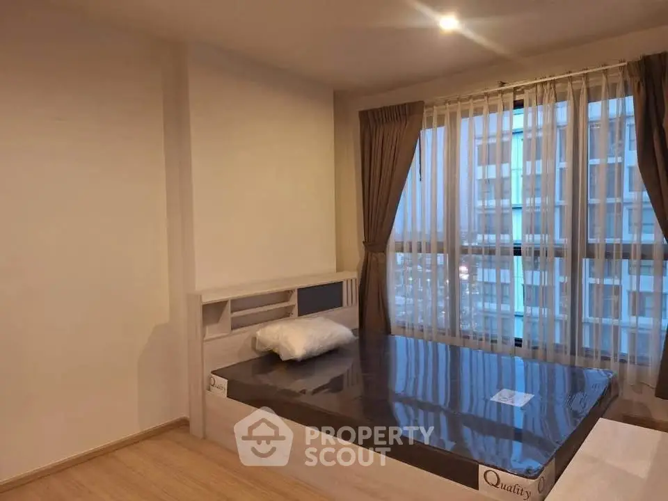 Spacious bedroom with large windows and modern design in a high-rise apartment.