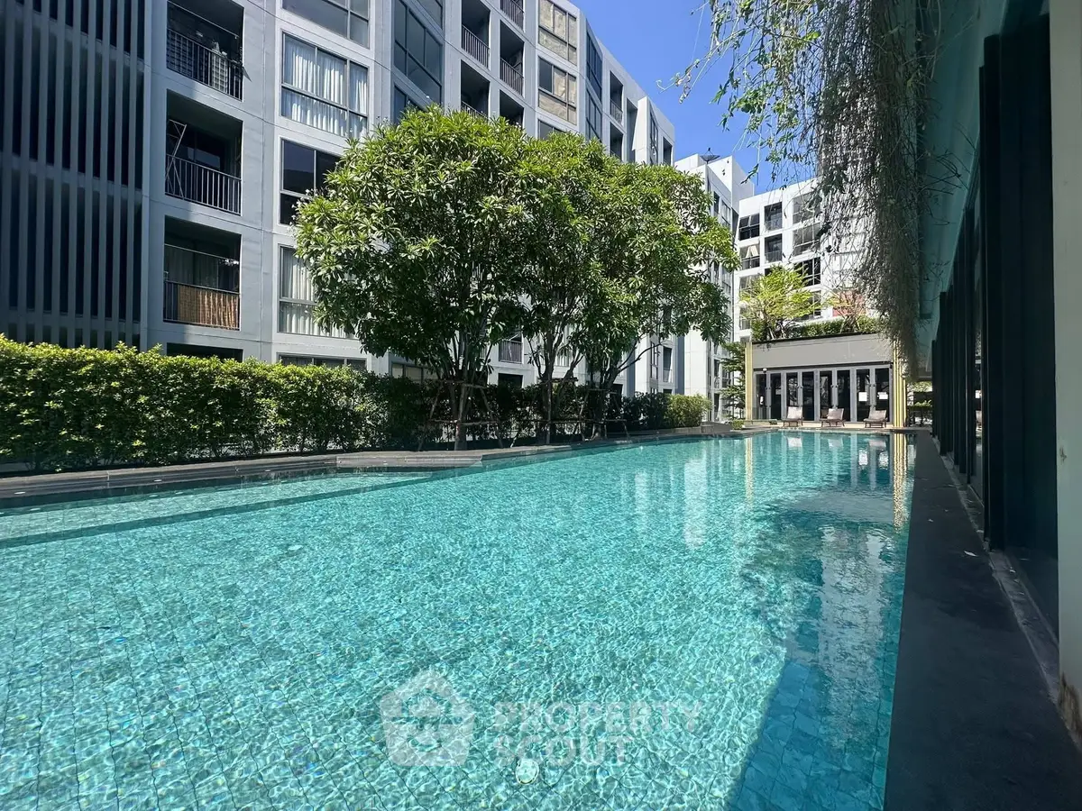 Luxurious apartment complex with sparkling pool and modern architecture, perfect for urban living.