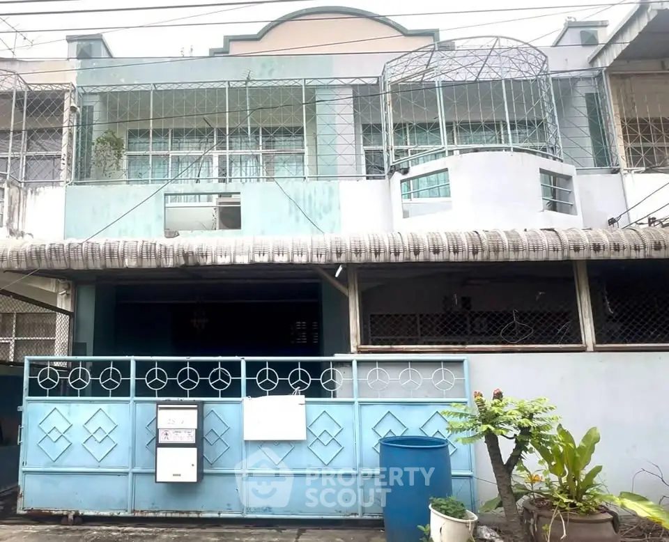 Charming two-story residential building with unique architectural design and gated entrance.