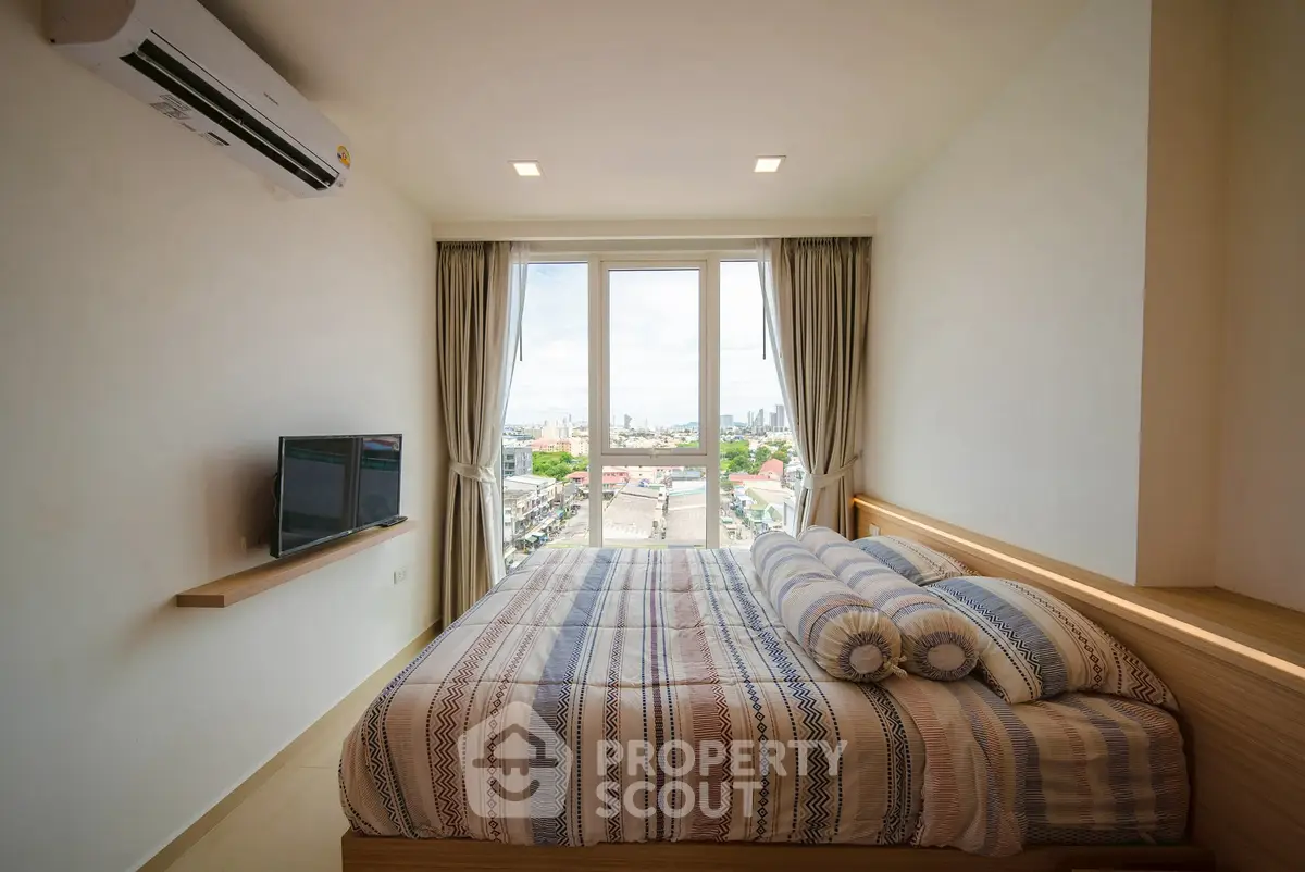 Modern bedroom with city view, featuring cozy bed and wall-mounted TV.