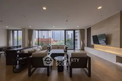 Spacious modern living room with large windows and city view, featuring elegant furniture and sleek design.