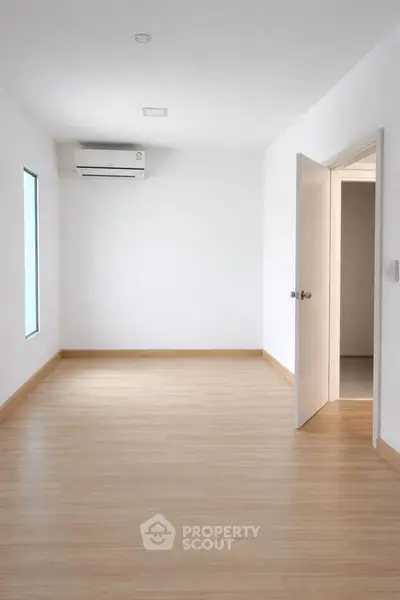 Spacious empty room with wooden flooring and air conditioning, perfect for customization.