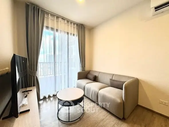 Modern living room with cozy sofa and large window, perfect for relaxation.