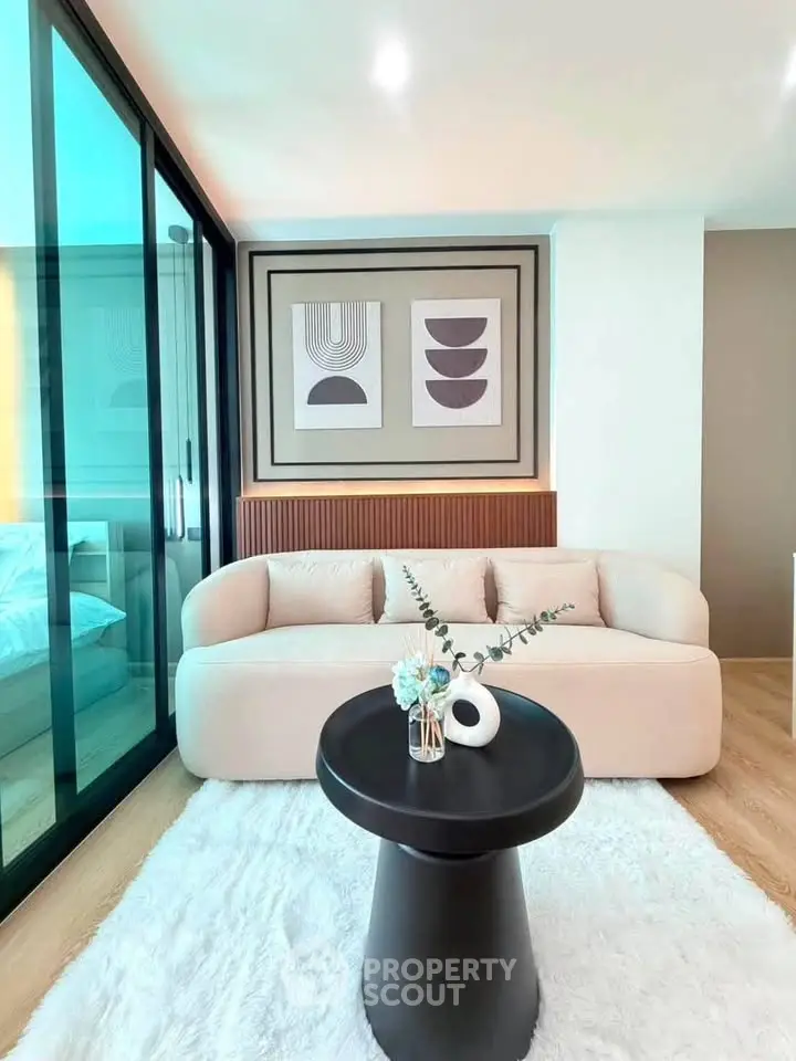 Modern living room with stylish decor and cozy seating area, featuring elegant artwork and a plush rug.