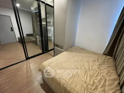 Modern bedroom with mirrored closet doors and cozy bedding in stylish apartment.
