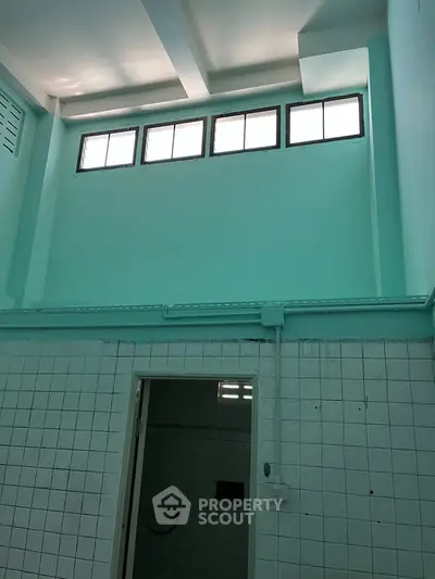 High-ceiling interior with tiled walls and small windows, ideal for creative renovation.