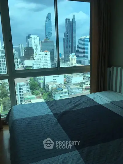 Stunning city view from a modern bedroom with large windows and cozy bedding.