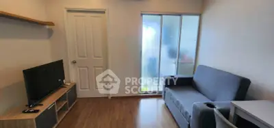 Cozy living room with modern furniture and wooden flooring, featuring a TV and a comfortable sofa.