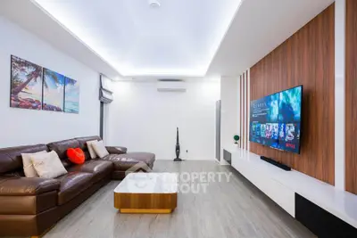 Modern living room with sleek design, featuring a large TV, stylish furniture, and elegant lighting.