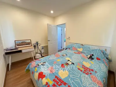 Cozy bedroom with colorful bedding and modern decor in a well-lit space.