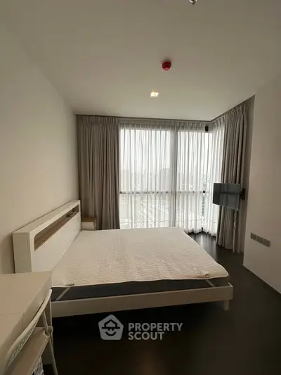 Modern bedroom with large windows and minimalist decor in a high-rise apartment.