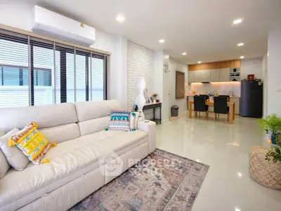 Spacious modern living room with open kitchen, stylish decor, and ample natural light.