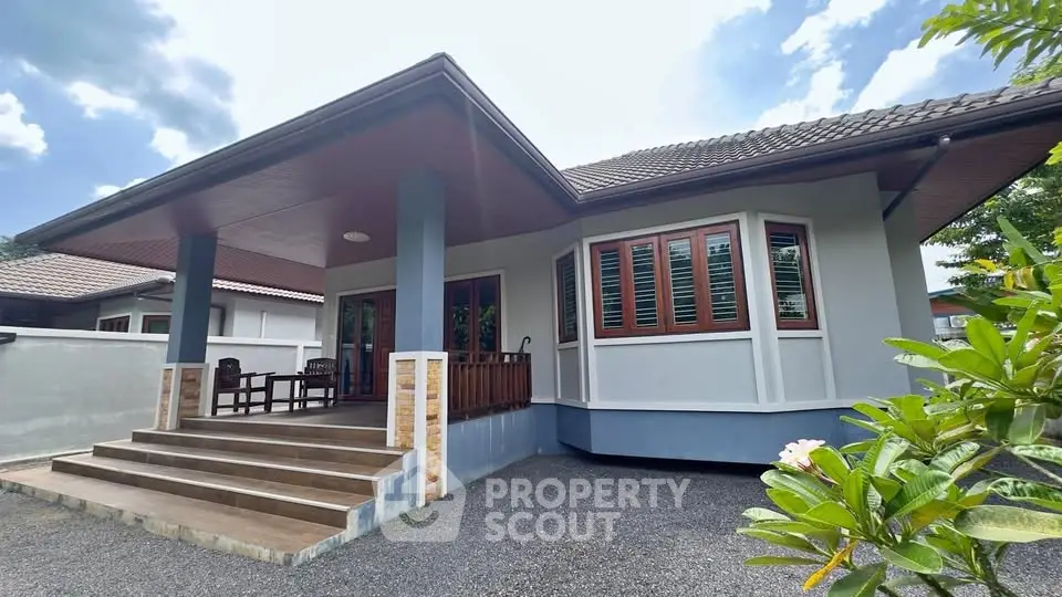 Charming single-story house with inviting porch and lush greenery