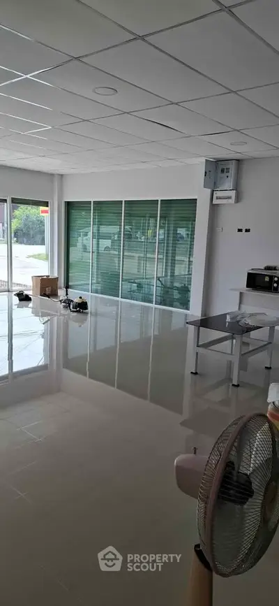 Spacious commercial space with large windows and glossy tiled floors, ideal for retail or office setup.