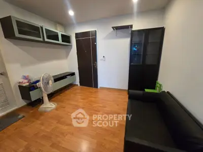 Modern living room with wooden flooring, sleek black sofa, and stylish storage cabinets.