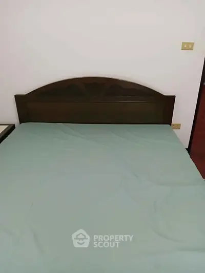 Cozy bedroom with simple wooden headboard and soft bedding