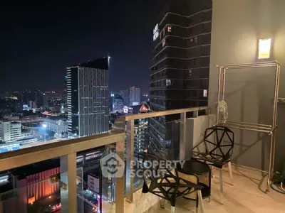 Stunning cityscape view from a modern balcony at night, featuring stylish outdoor seating.