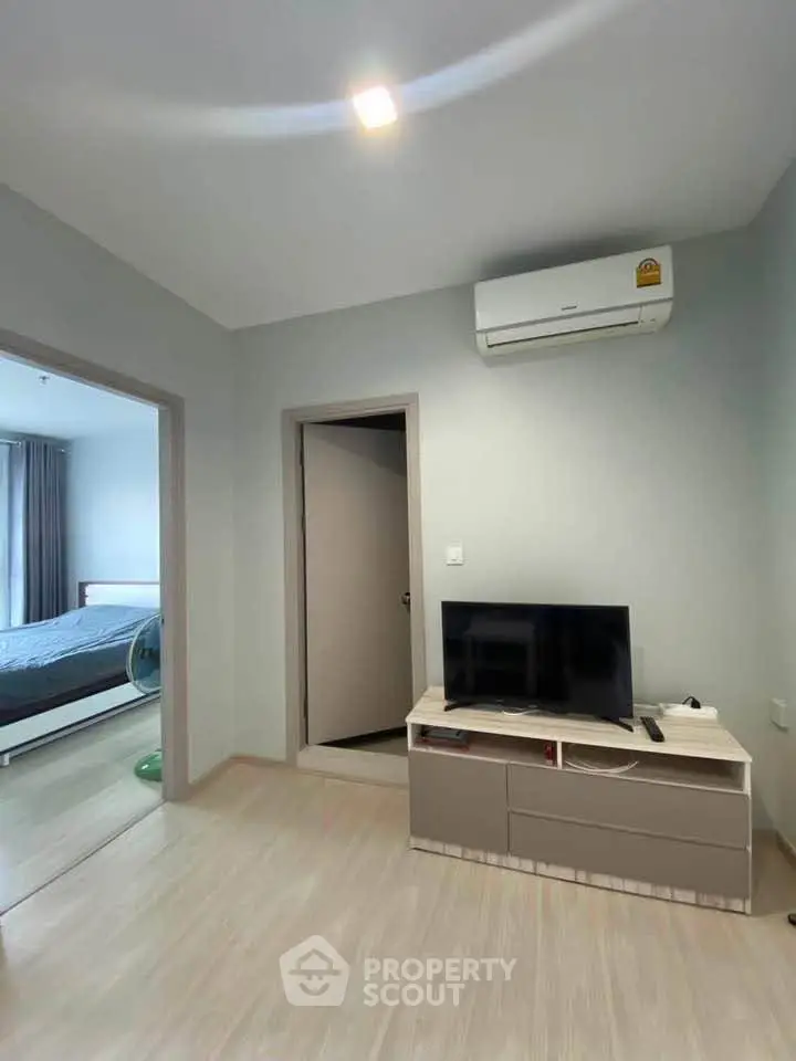 Modern living room with TV and air conditioning, adjacent to a cozy bedroom.
