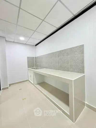 Modern minimalist kitchen with sleek countertops and tiled backsplash in a bright, spacious layout.