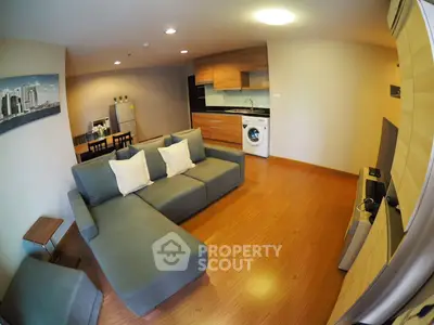 Modern open-plan living room with kitchen and washing machine, featuring stylish furniture and wooden flooring.
