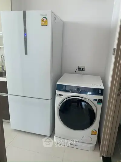 Modern kitchen with sleek fridge and washing machine in compact layout.