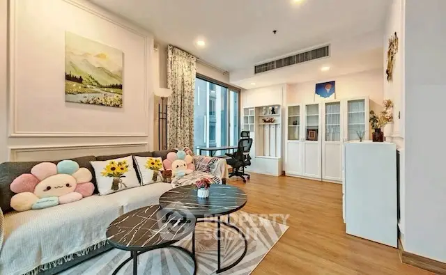 Charming living room with cozy decor and modern furniture, featuring a large window and stylish coffee tables.