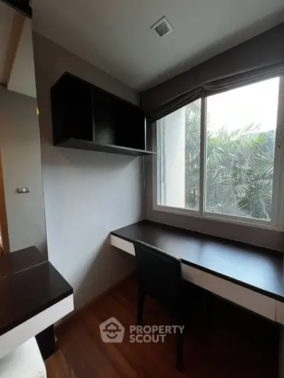 Modern study room with sleek desk and chair, large window with lush greenery view, and stylish shelving.