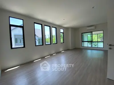 Spacious sunlit room with large windows and modern flooring, perfect for a stylish living area.