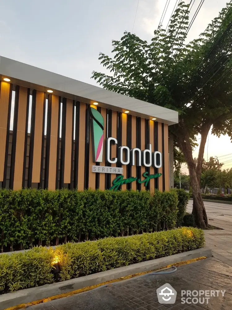 Modern condo entrance with stylish signage and lush greenery