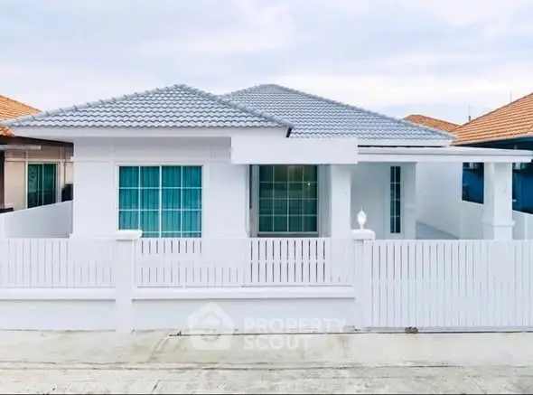 Charming single-story white house with modern design and spacious front yard.