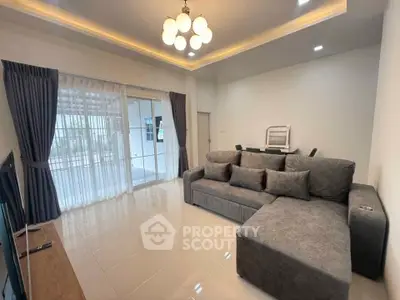 Spacious living room with modern gray sofa and elegant lighting, featuring large windows with curtains.