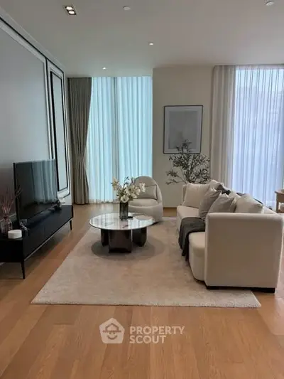 Elegant living room with modern decor, large windows, and cozy seating area.