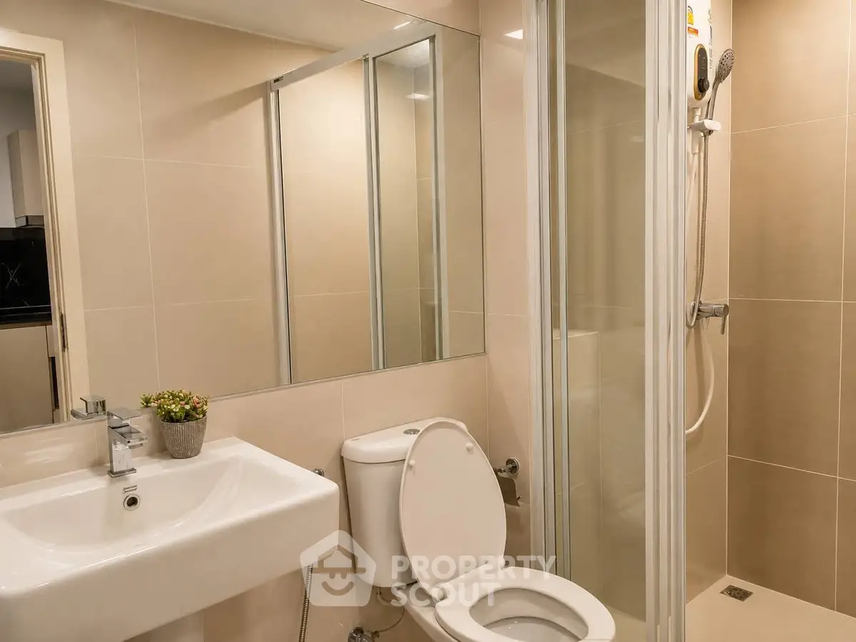 Modern bathroom with glass shower and sleek fixtures in contemporary apartment.