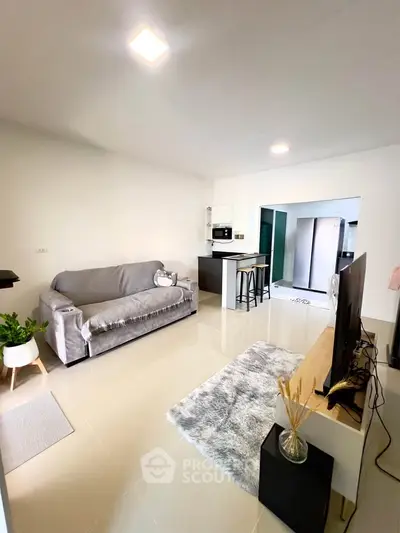 Modern living room with open kitchen, stylish decor, and cozy seating area.